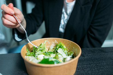 eating vegetarian salad in a cardboard ecological paper container in the office.