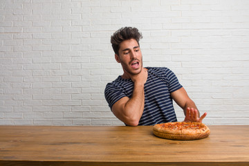 Young handsome and natural man sitting on a table worried and overwhelmed, anxious feeling...