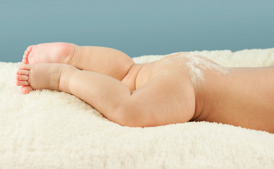 Naked butt of a baby with powdered irritation and prysy at the doctor’s appointment on an isolated blue background. Concept of child