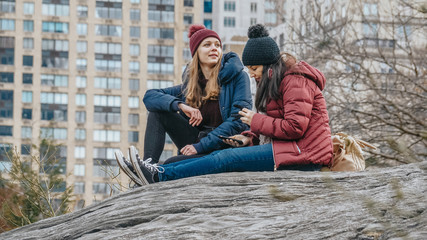 Two girls sit on a rock in Central Park New York