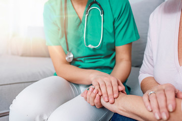 Close-up of person touching hand of senior woman. Caregiver in the nursing home