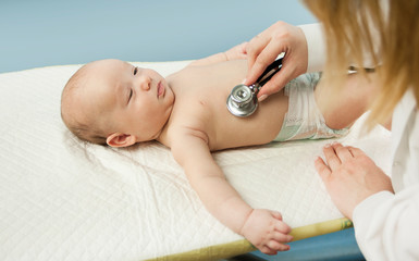 small child, child, lies in the doctor's office, and the doctor listens to the lungs, heart. The concept of children's health