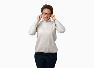 Young beautiful african american woman wearing glasses over isolated background covering ears with fingers with annoyed expression for the noise of loud music. Deaf concept.