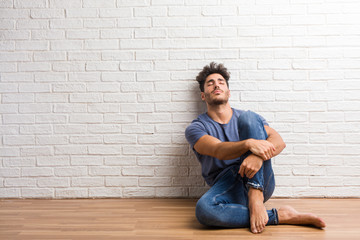 Young natural man sit on a wooden floor proud and confident, pointing fingers, example to follow,...