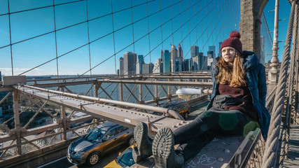 Fototapeta na wymiar Young beautiful woman on Brooklyn Bridge New York enjoys a wonderful sunny day