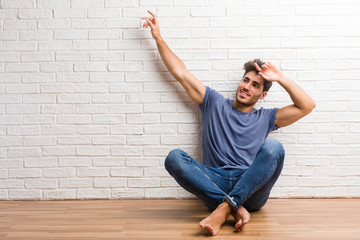 Young natural man sit on a wooden floor listening to music, dancing and having fun, moving, shouting and expressing happiness, freedom concept