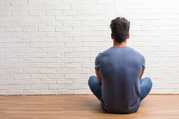 Young natural man sit on a wooden floor showing back, posing and waiting, looking back - Powered by Adobe