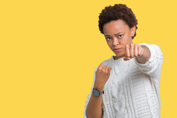 Beautiful young african american woman wearing sweater over isolated background Punching fist to fight, aggressive and angry attack, threat and violence