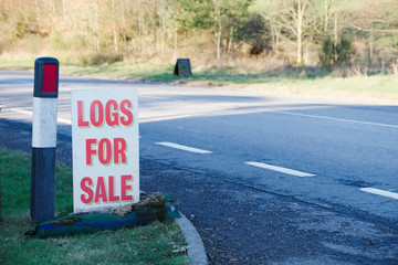 Logs wood for sale sign at farm shop for biomass burner