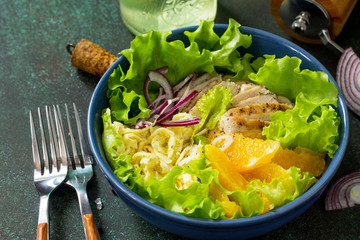 Diet menu. Healthy salad with chicken, egg pancakes, orange, green salad and dressing vinaigrette on stone table. Top view flat lay background. Copy space.