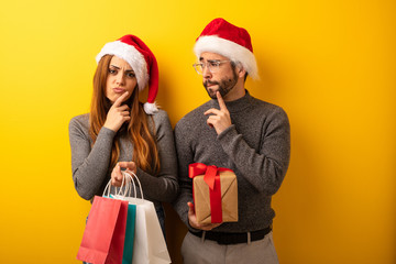 Couple or friends holding gifts and shopping bags doubting and confused