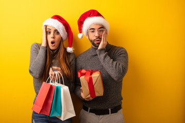 Couple or friends holding gifts and shopping bags surprised and shocked