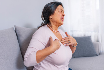 Cardiac pain. Mature woman holds her heart