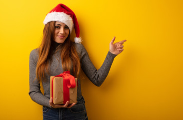 Young pretty woman holding gift pointing to the side with finger