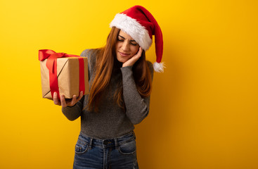 Young pretty woman holding gift covering ears with hands