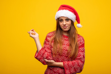Young woman wearing santa hat pointing to the side with finger