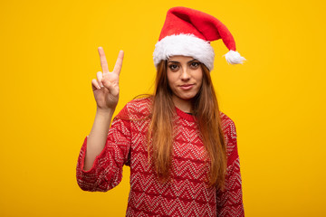 Young woman wearing santa hat showing number two