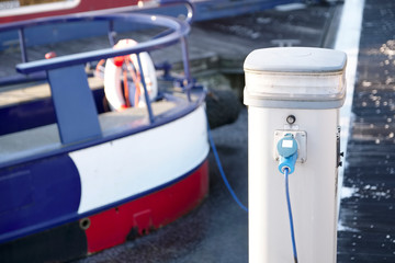 Electric charging point for boat and barge at marina mooring on canal - obrazy, fototapety, plakaty
