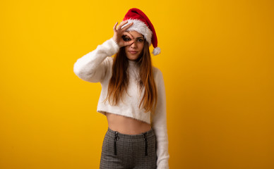 Young pretty woman holding gift confident doing ok gesture on eye