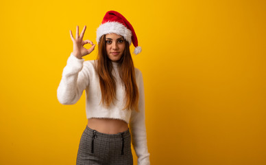 Young pretty woman holding gift cheerful and confident doing ok gesture