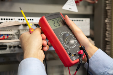 Multimeter in electrician hands. Engineer working in electrical circuits.