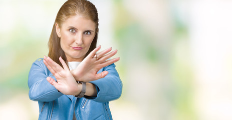 Beautiful middle age mature woman wearing fashion leather jacket over isolated background Rejection expression crossing arms and palms doing negative sign, angry face