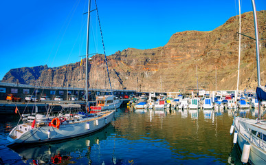 Panoramic view of Puerto de Santiago with traditional boat and yacht in the harbor