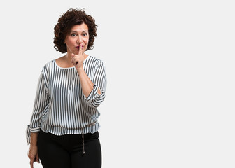 Middle aged woman keeping a secret or asking for silence, serious face, obedience concept