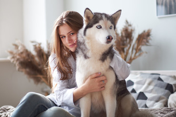 blonde girl playing with her dog husky at home. © yavdat