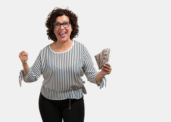 Middle aged woman very excited and euphoric, shouting looking forward, celebrating a victory and...