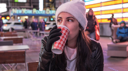 Young woman drinks a cup of coffee in the streets of New York