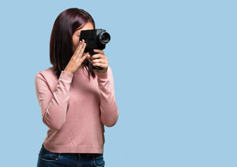 Young pretty woman excited and entertained, looking through a film camera, looking for an...