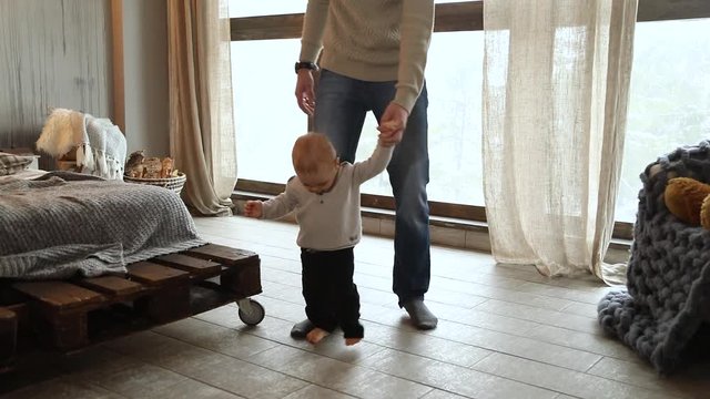 Baby taking first steps, child learning to walk. Slow motion