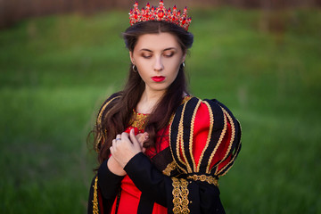 Fototapeta na wymiar beautiful, young girl in black and red medieval dress with crown on head.