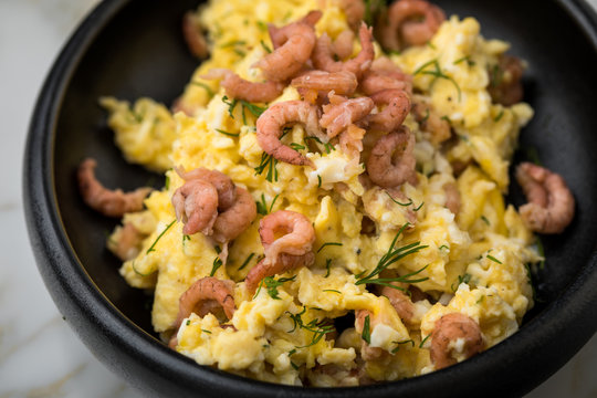 Krabben R&uuml;hrei mit Friesischen Nordseekrabben und Dill in schwarzer Schale auf Marmor Hintergrund