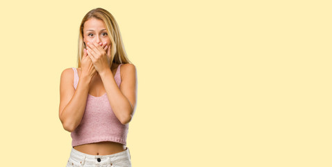 Portrait of young pretty blonde woman covering mouth, symbol of silence and repression, trying not...