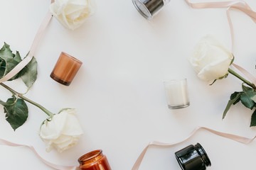 Spa composition of white roses, scented candles and ribbons on a white background, flat, top view