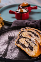 Poppy seed strudel on dark plate with silhouette of fork made by sugar
