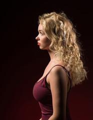 Naklejka premium Beautiful woman with blonde long curly hair. Beauty portrait of modern fashion, red background.