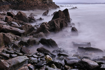 BLACK ROCKS ON THE COAST SURROUNDED WITH A MAGIC AND MYSTERIOUS FOG