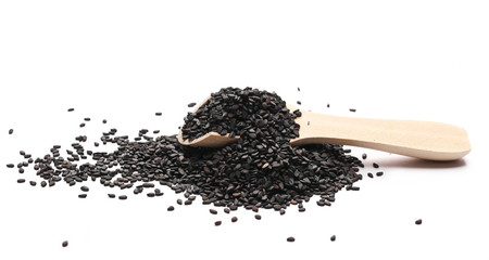 Black organic sesame seeds in wooden spoon isolated on white background