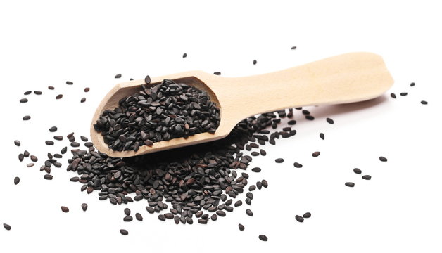 Black organic sesame seeds in wooden spoon isolated on white background