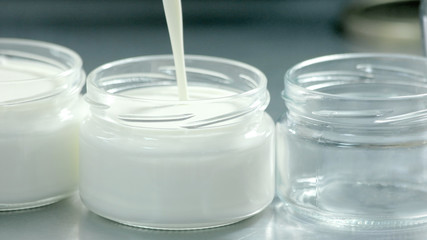Fresh milk is poured into glass jars close up. Fresh milk in transparent pots. How to make kefir at home.