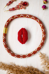 Beaded necklace and brooch set. Red garnet  soutache jewelry on the white wooden background. Women accessories