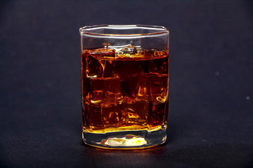 Glass of whiskey with ice or brandy isolated on a black background. Whiskey with ice in the glass...