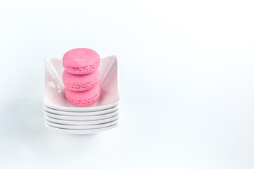 Several sweet tasty pink macarons in a pile of small white bowls with copy space closeup