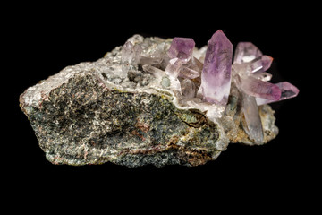 Macro mineral stone Amethyst crystals in rock on a black background