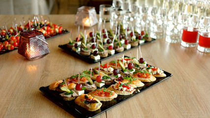 Delicious appetizer at served table in restaurant. Bruschetta with cherry tomato, mozzarella and salmon. Beautifully decorated catering banquet table.