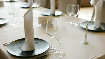 Banquet table set. Empty wine glasses, plate, napkins and cutlery are on table. Table served for special occasion in restaurant.