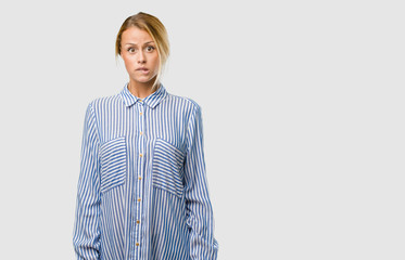 Portrait of a young pretty blonde woman worried and overwhelmed, forgetful, realize something,...
